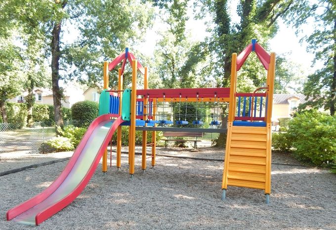 l'aire de jeux pour les enfants : balançoire, trois mobiles et une maisonnette avec toboggan.